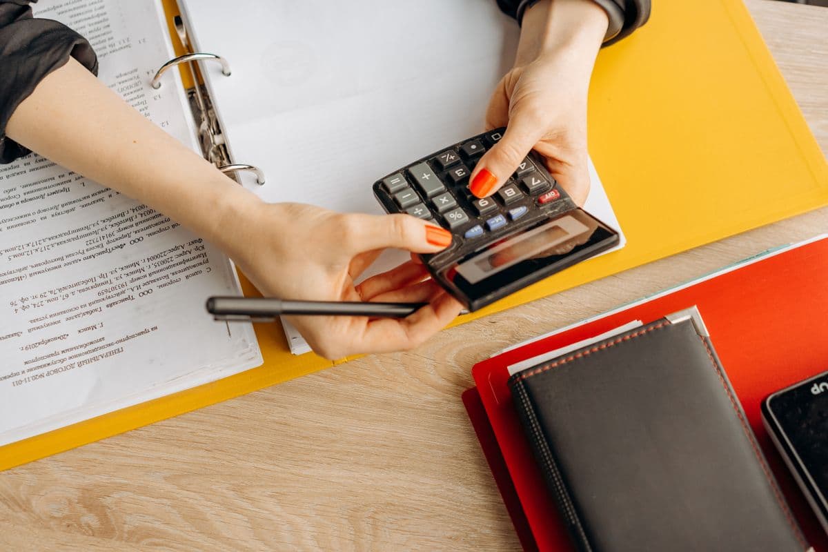 A person reviewing commission figures with a calculator